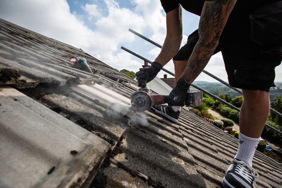 Cutting a roof tile with a grinder to make room for a roof hook