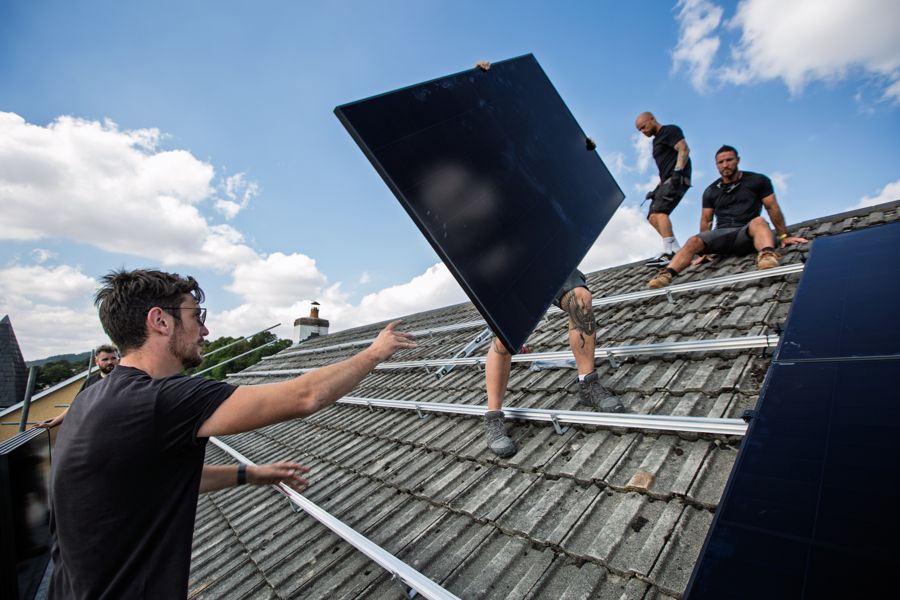 Three of the team passing a panel over the scaffold onto the roof