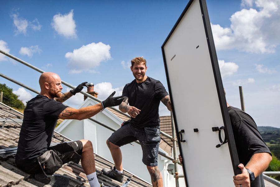 A solar panel being passed up from the scaffold to the roof