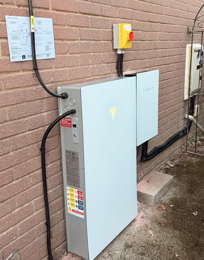 The Powerwall installation with isolator and system schematic label on the wall above