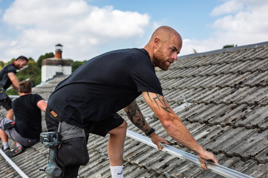 Lifting a mounting rail into position on the roof