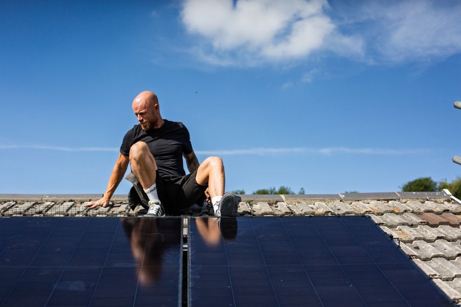 An installer sitting on the roof beside the completed array