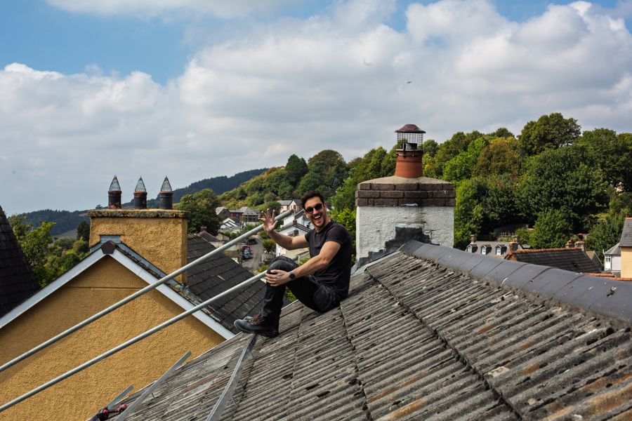 One of the team sitting on the roof by the chimney, waving